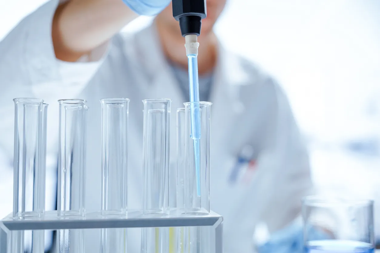 Professionnelle de laboratoire pipetant soigneusement un échantillon dans un tube